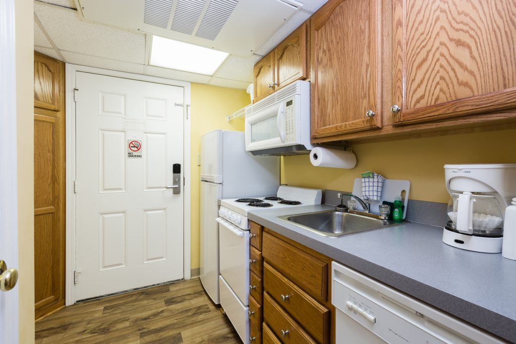 A kitchen with a sink, stove, microwave, and coffee maker.